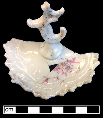 European hard paste porcelain ring holder decorated with a floral decal and gold gilt. Printed mark “Victoria Carlsbad Austria” dates 1891-1918. Similar example shown right.